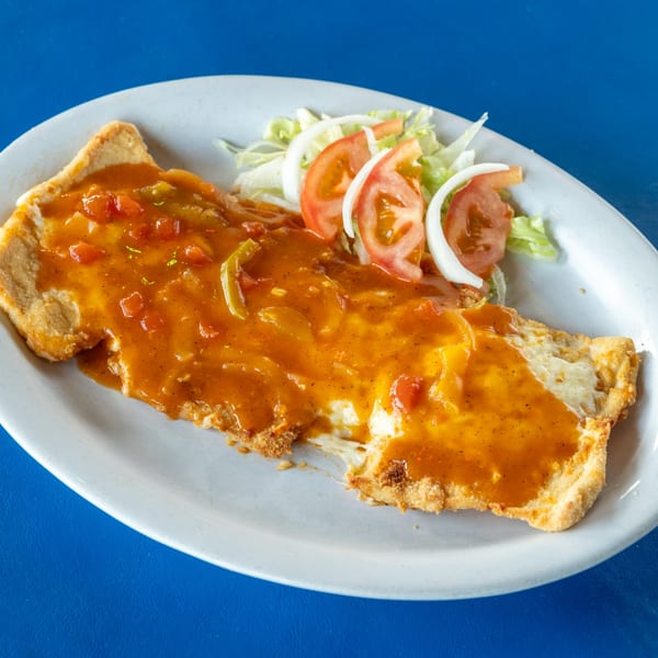 Fried fish fillet covered in a rich orange sauce with diced tomatoes, onions, and a side salad.