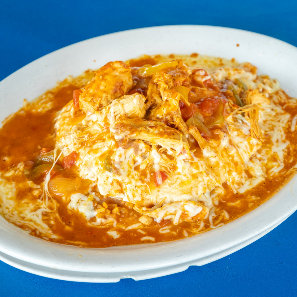 A white plate filled with chicken and vegetables in a rich orange sauce, topped with melted cheese.
